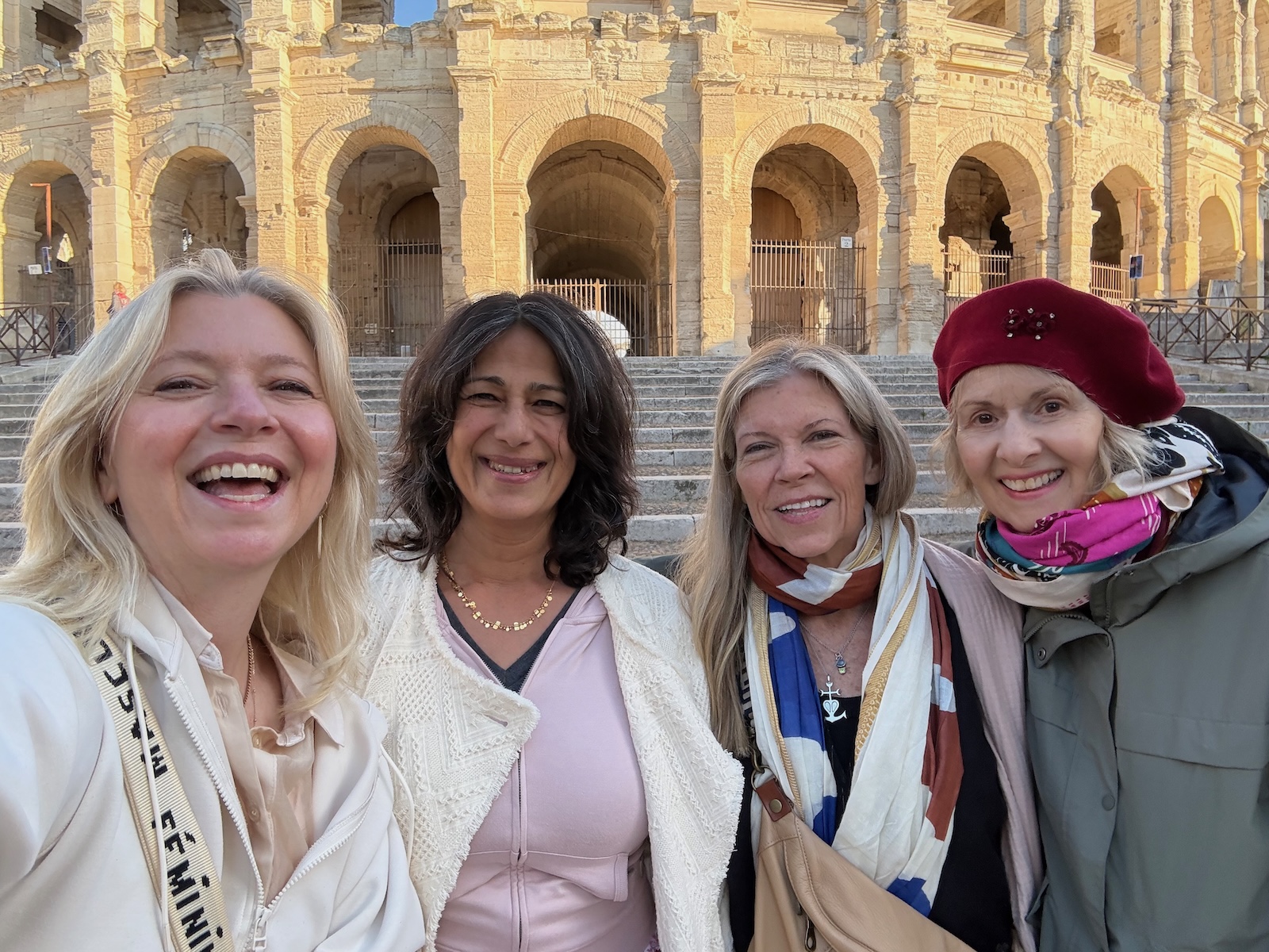 Four Furies writers embracing and laughing in front of the Roman arena in Arles
