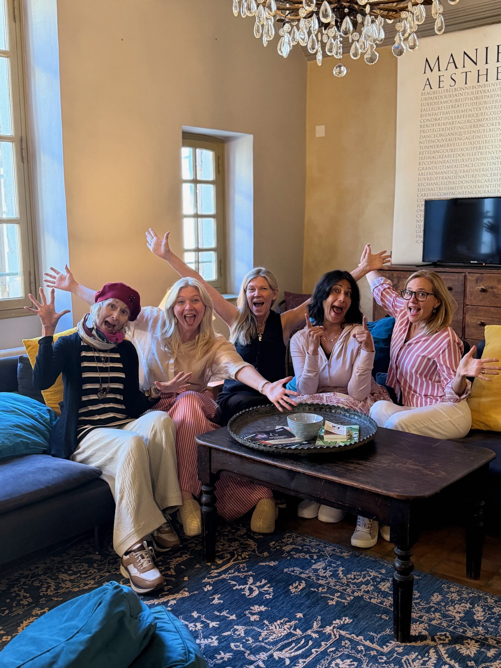 Five writers in a sun-filled Arles salon, arms raised in joy