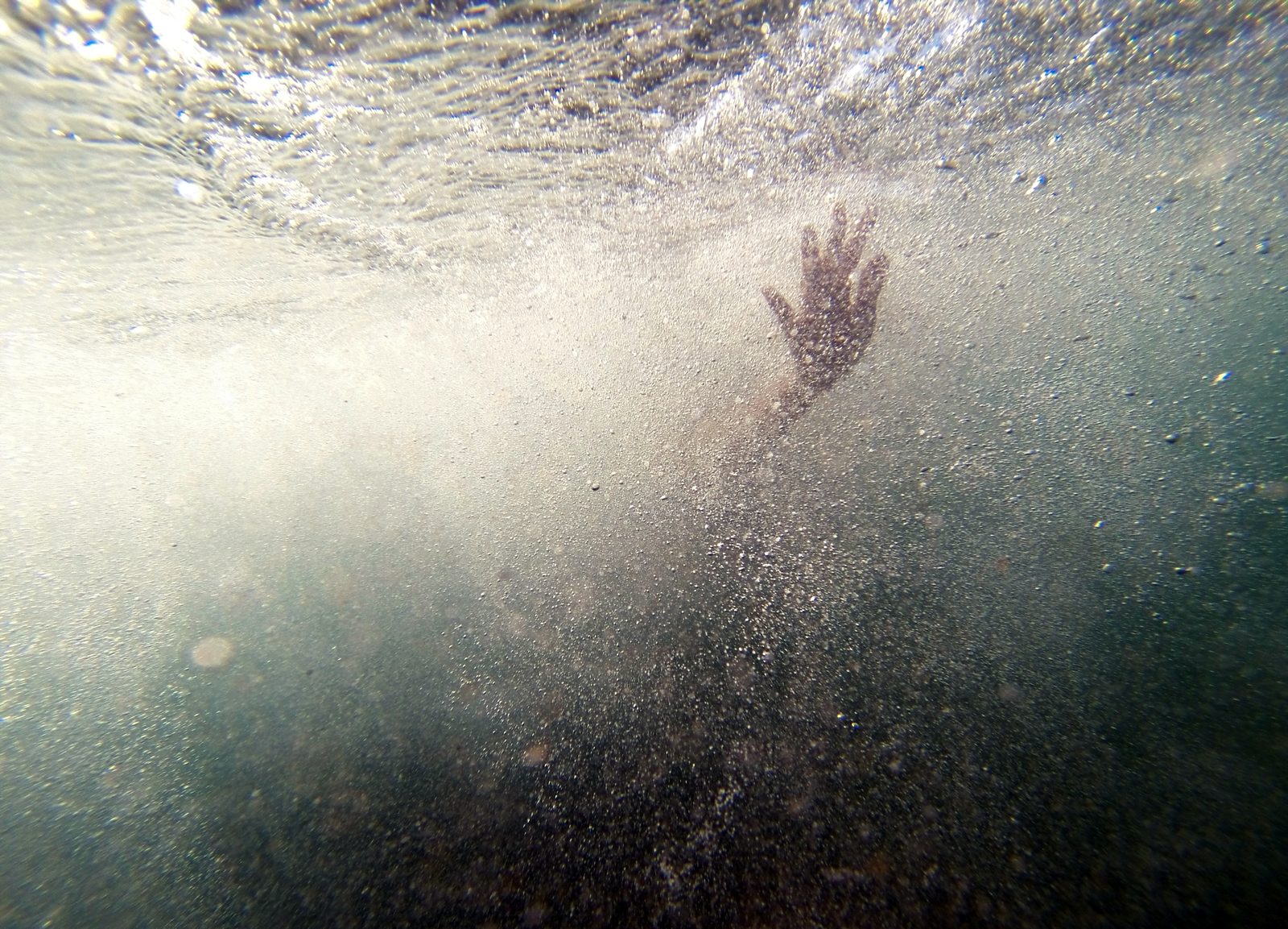 A hand reaching up through dark water